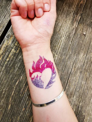 Lila und rosa Herz mit Flammenmuster auf dem Handgelenk.